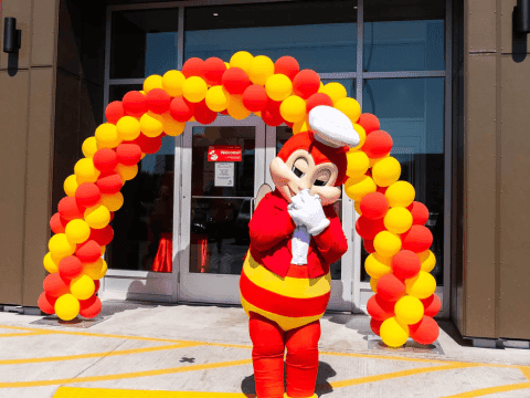 Jollibee mascot in front of balloon arch